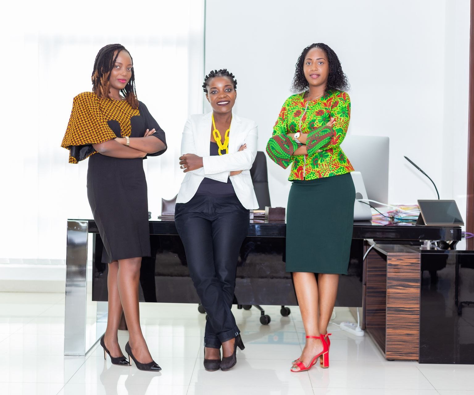Three African businesswomen smiling in a modern office